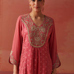 Close-up of a woman wearing a pink embroidered georgette kurta with floral threadwork and a scalloped hem, paired with pink trousers