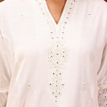 Model posing in Inaya ivory embroidered cotton linen slub kurta with delicate embroidery on the chest and sleeves.