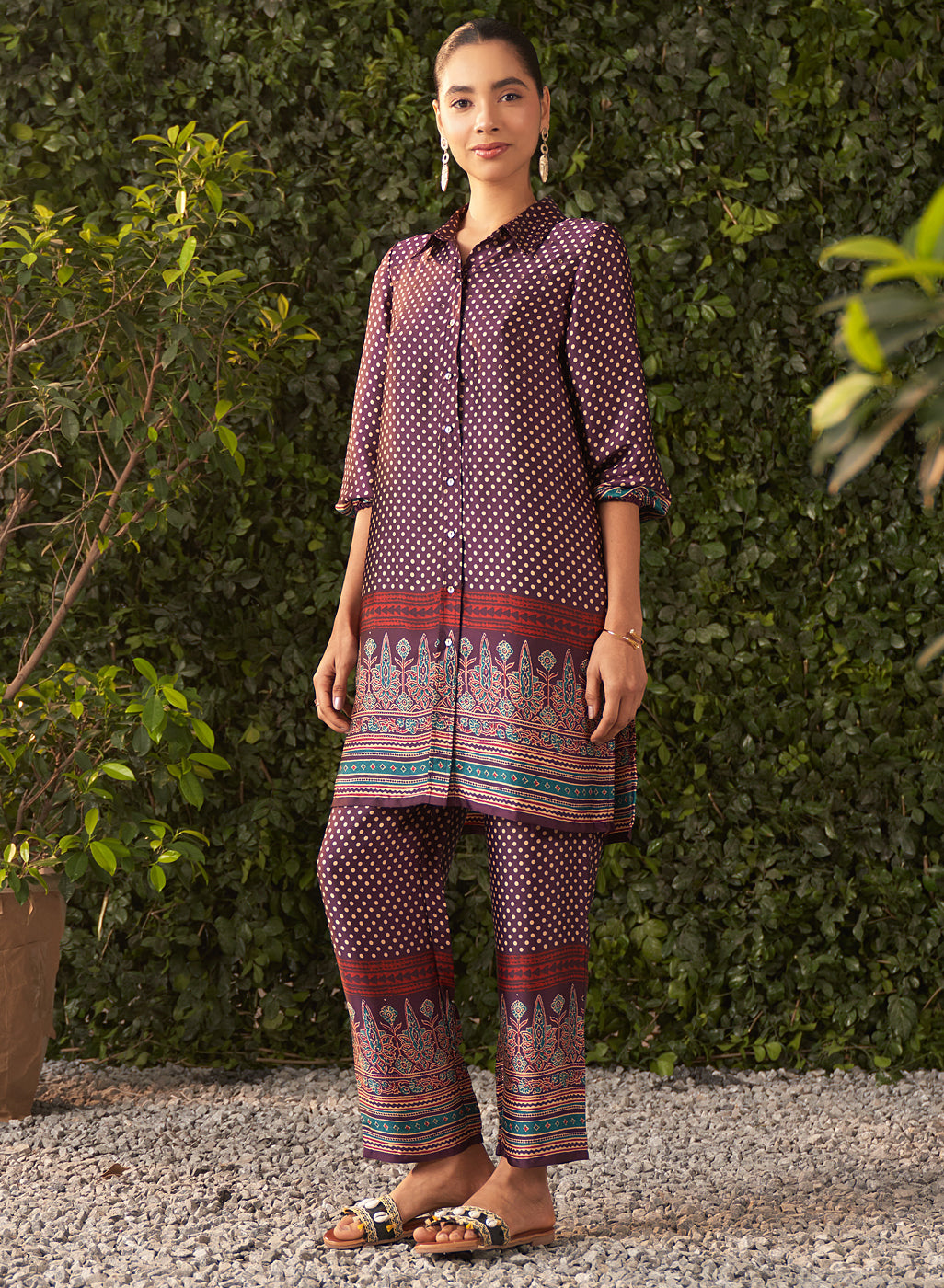 Elisa co-ord set in deep purple satin with gold polka dots and ornate border print, styled with statement earrings